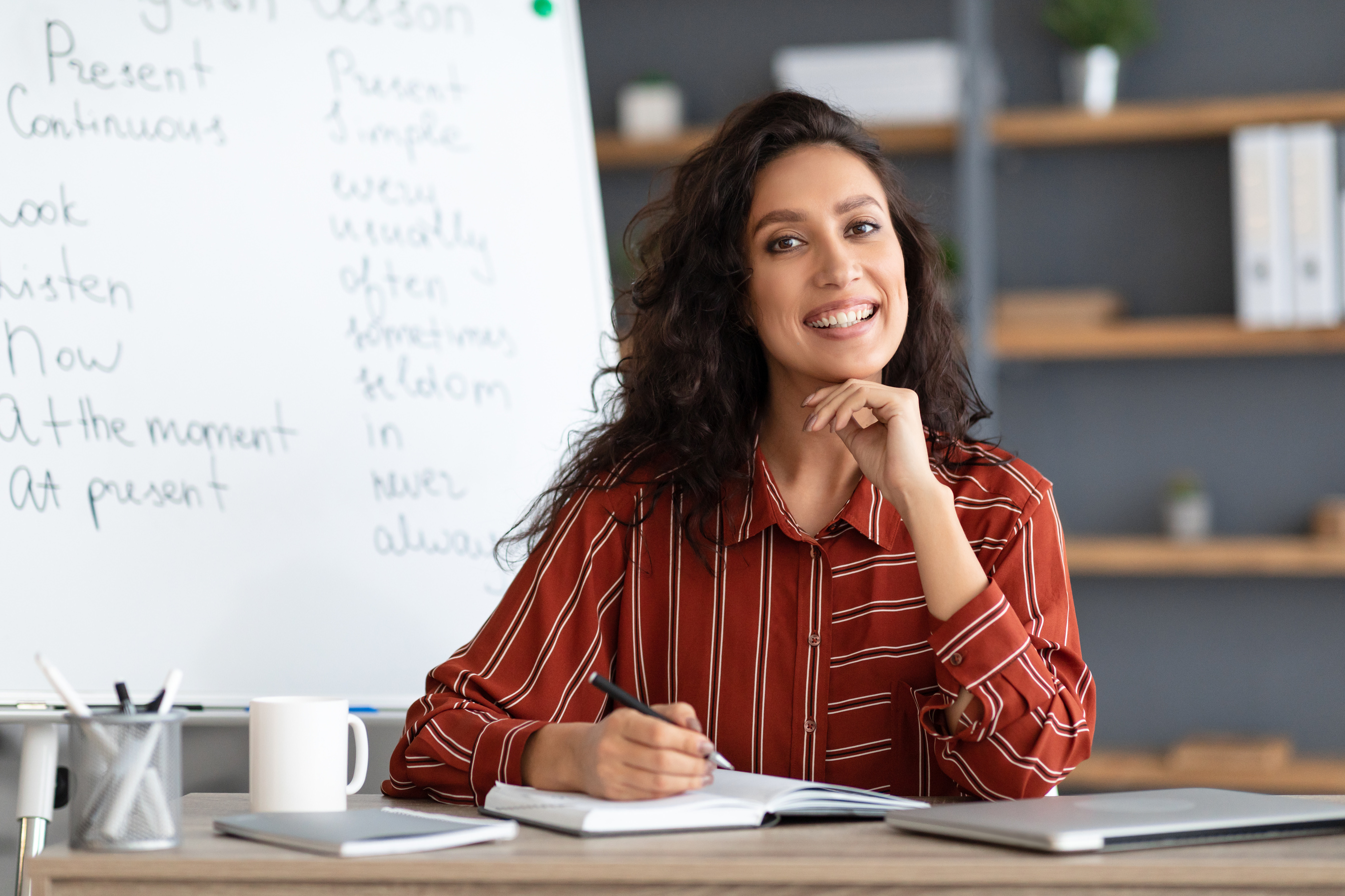 Female Teacher Sitting at Desk Looking at Camera